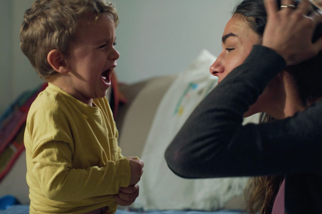 Mutter sitzt verzweifelt vor ihrem schreiendem Kind